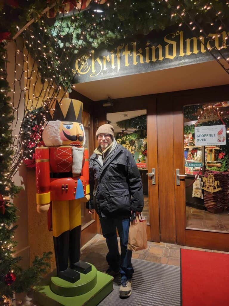 A man standing in front of a larger than life nutcracker in front of wooden doors