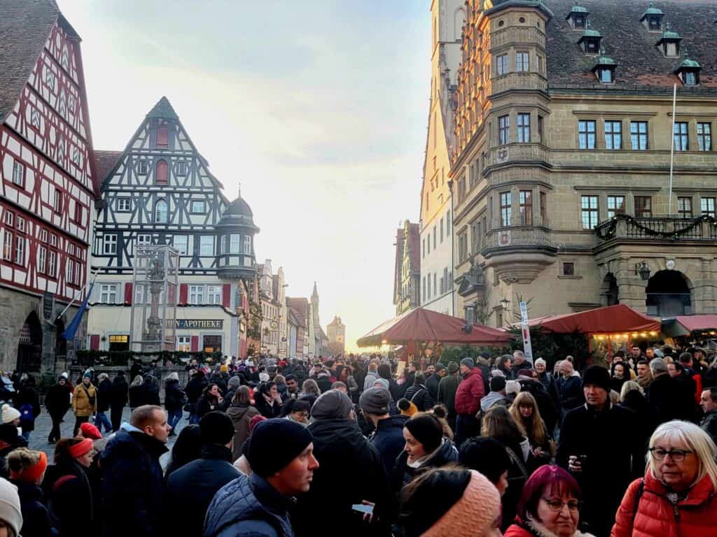 A medieval street absolutely packed with people in winter coats and hats