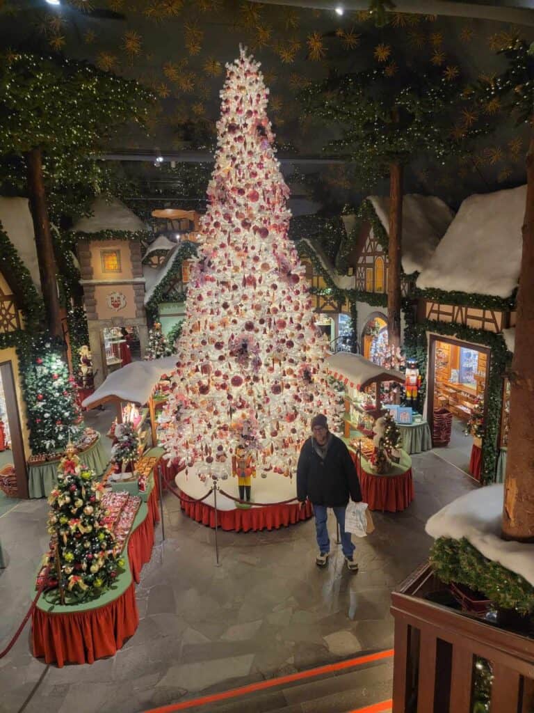 A man standing in a room full of christmas trees and faux cottages full of christmas decor