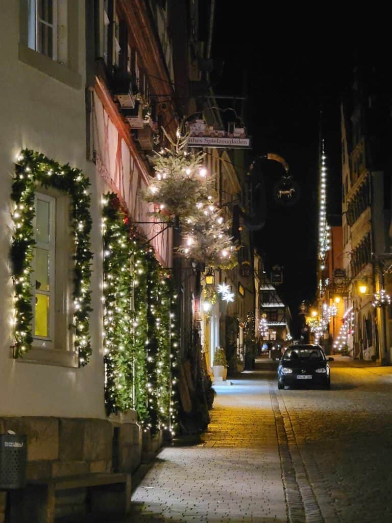 A street festively lit with white lights and garlands