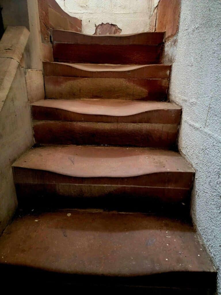 Red sandstone steps going up. They are worn down in the center from centuries of feet