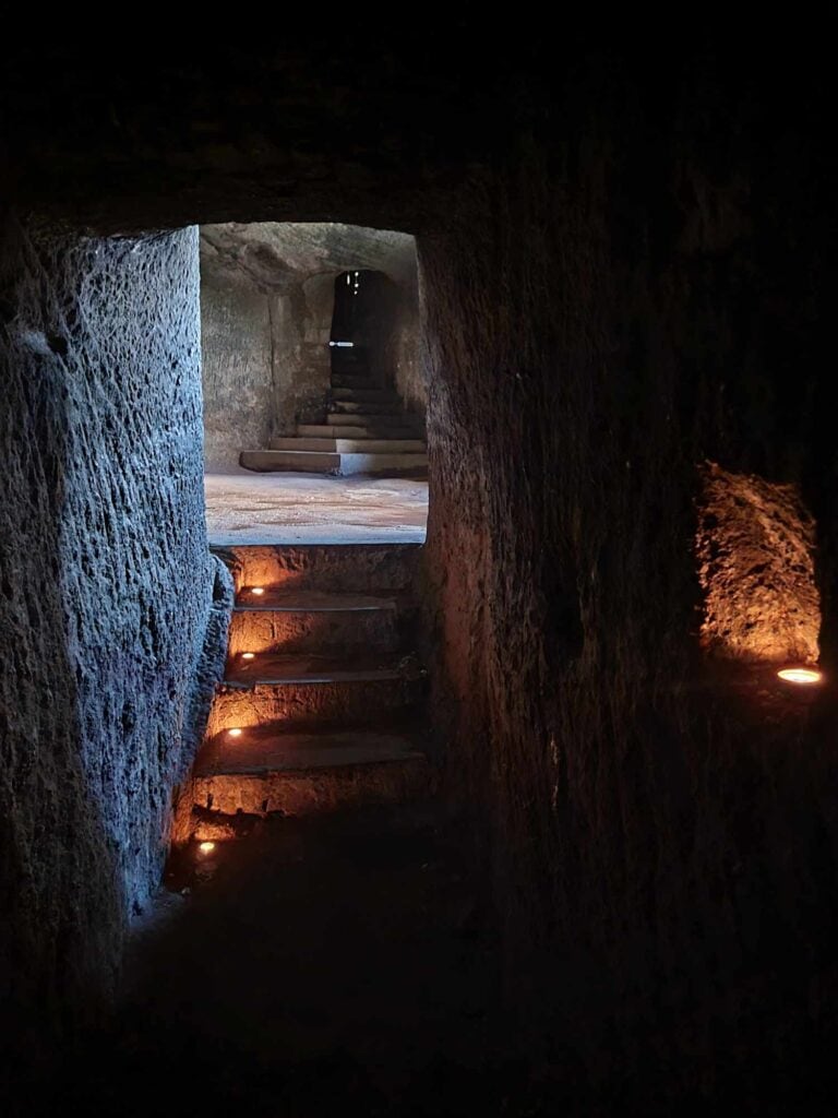 A dimly lit tunnel passage with stairs and one tealight on each step.