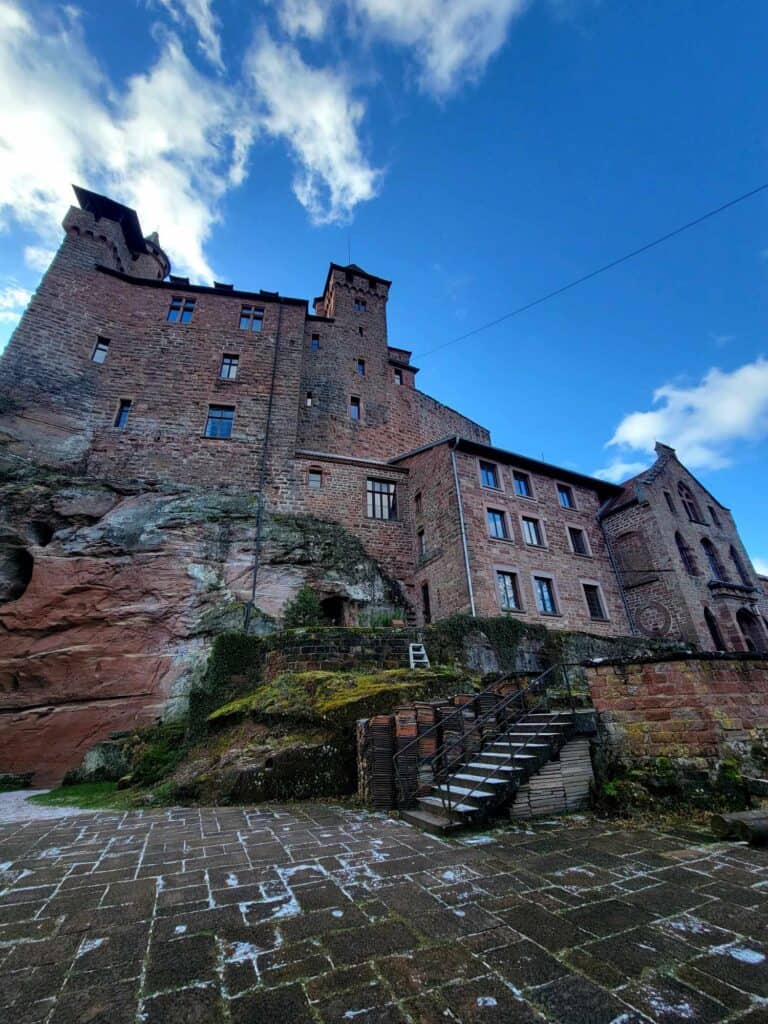 Berwartstein castle sitting atop a rock outcropping. There are stairs and a paved terrace below