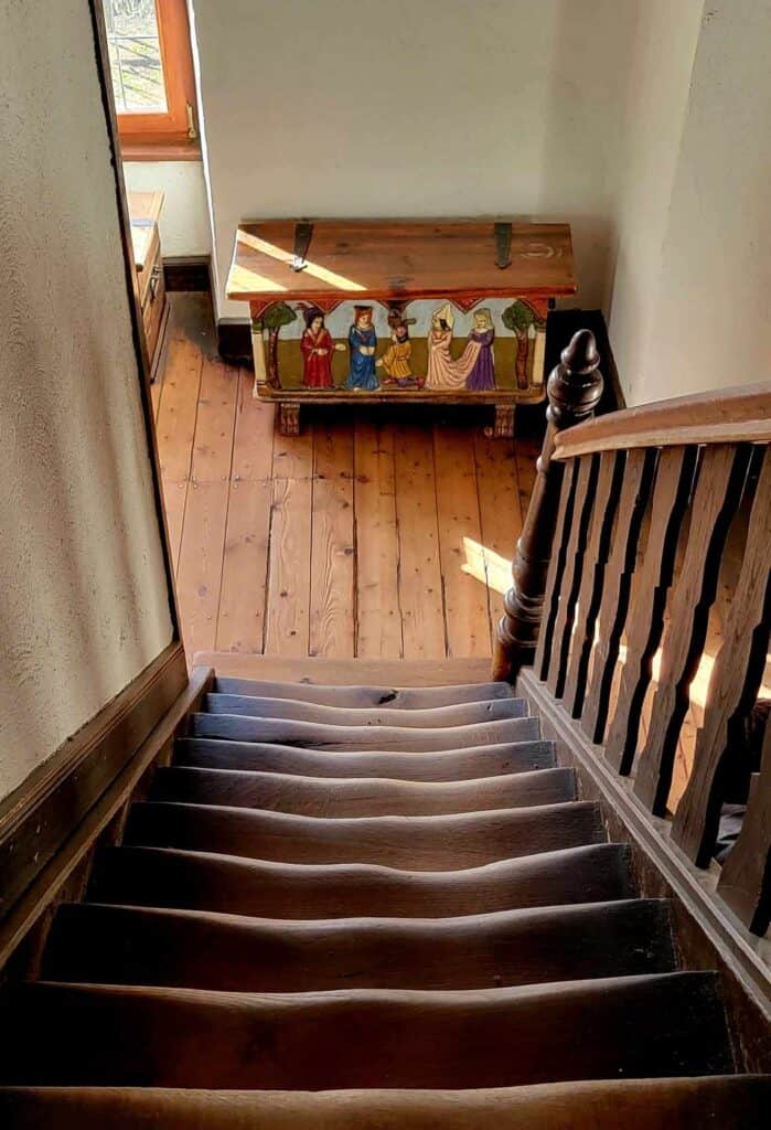 Looking down a flight of wooden stairs that is very worn and wavy