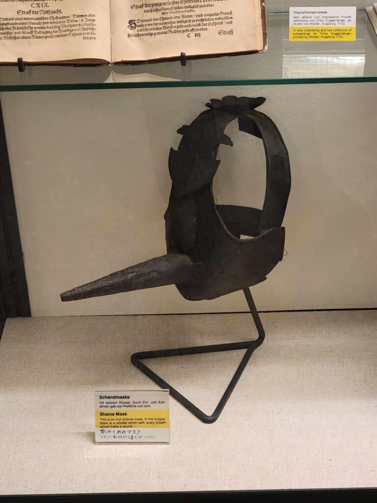 An iron contraption to be worn on the head with a very long beak-like protrusion and a wide jagged strap that went over the top of the head