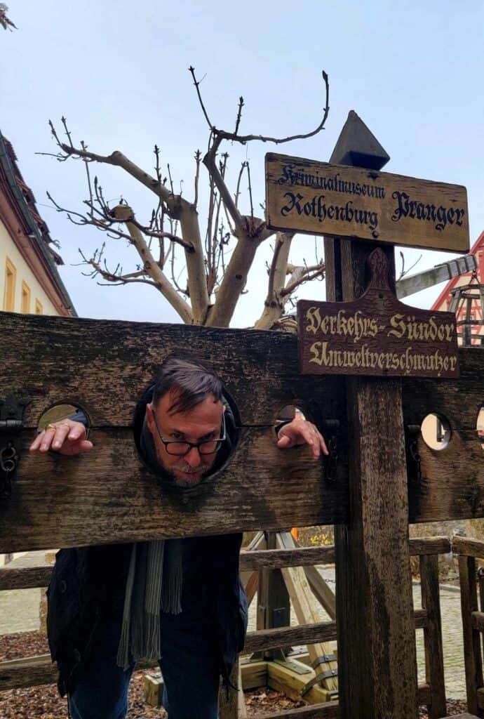 Man standing in a pillory with his head and wrists confined between two boards of wood