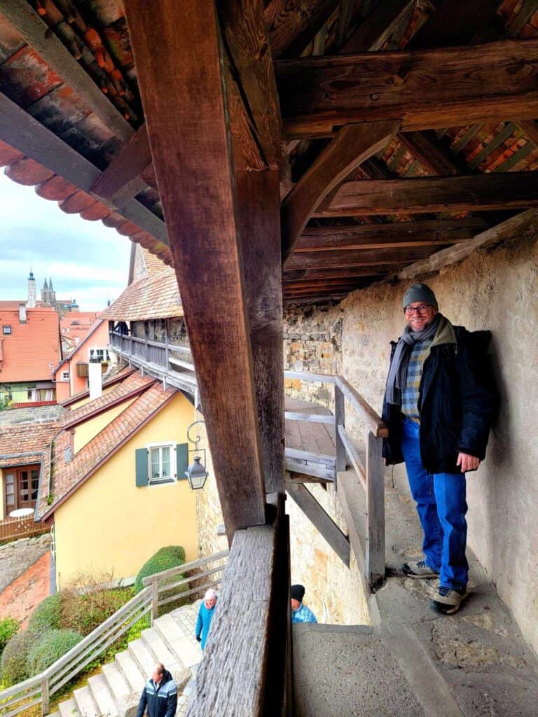 Man standing on a medieval wall ready to descend a flight of stairs