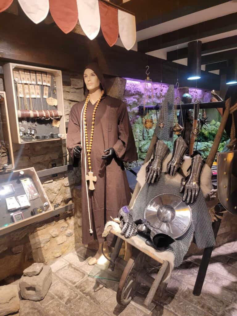 A mannequin dressed as a medieval monk surrounded by other medieval wares