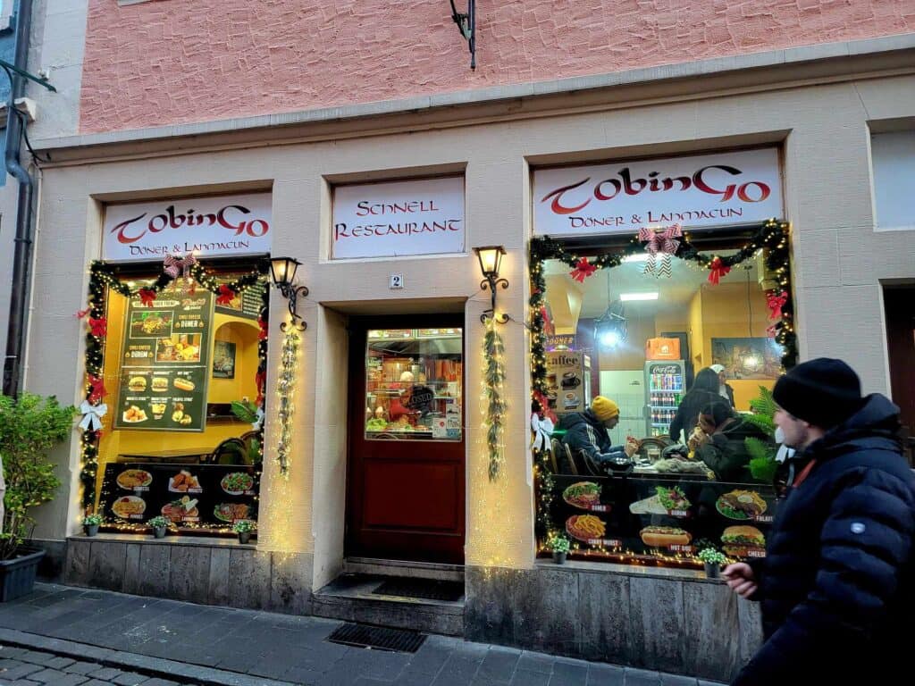 A restaurant with a sign "Schnell Restaurant" and people eating at tables