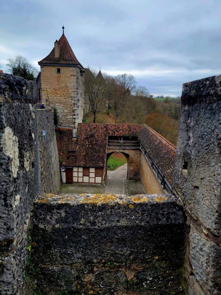 Stone walls, a half timbered house and a square tower with a pointed roof