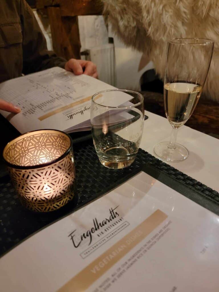 A candle, and wine glasses sit on a table with two menus 