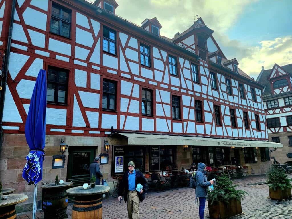 A large beautiful red and white timbered building with outdoor tables under an awning