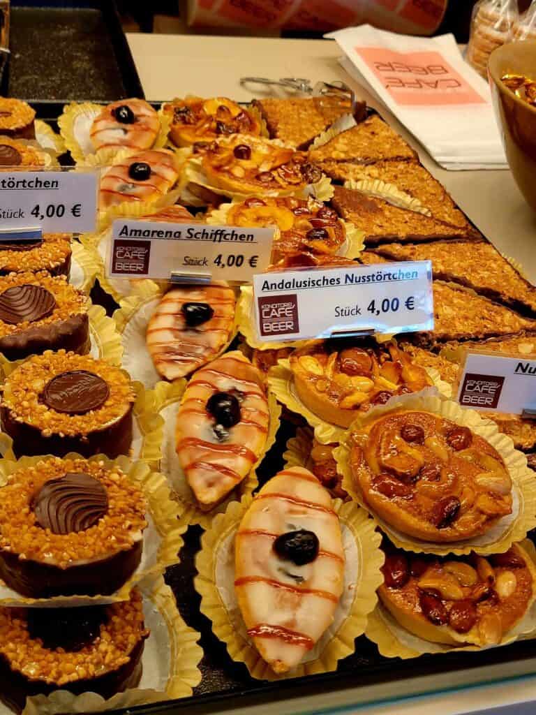 Incredible looking pastries in a case, covered with nuts, chocolate spread, fruits and drizzled syrup