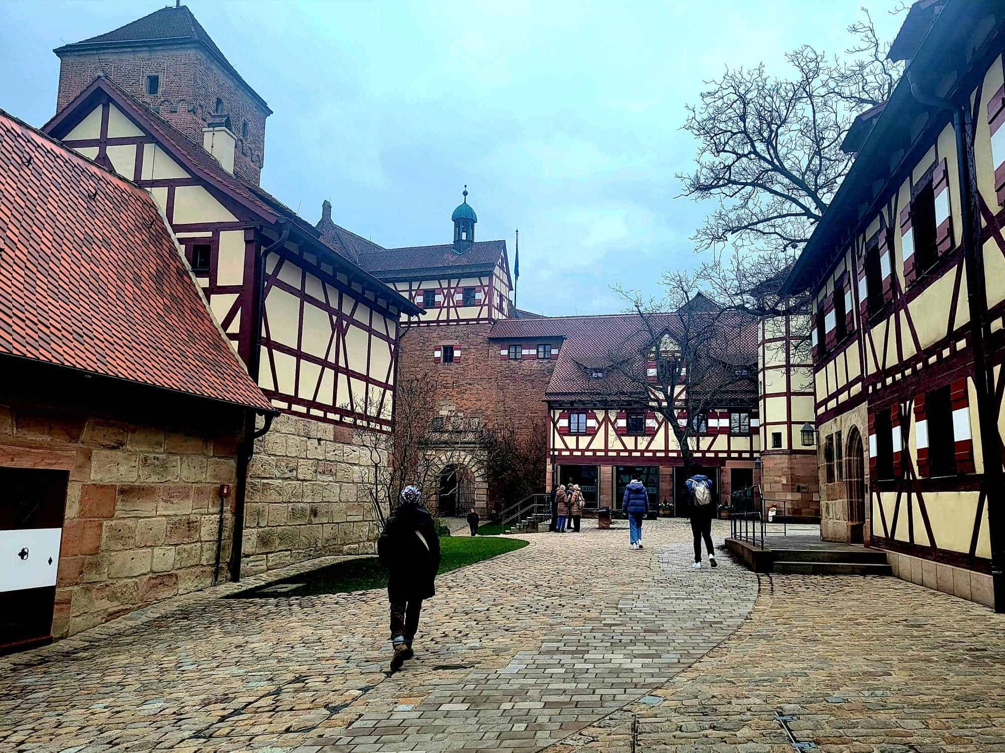 The courtyard of Nuremberg castle with cobblestone pavers and ringed with half-timbered buildings and a tower