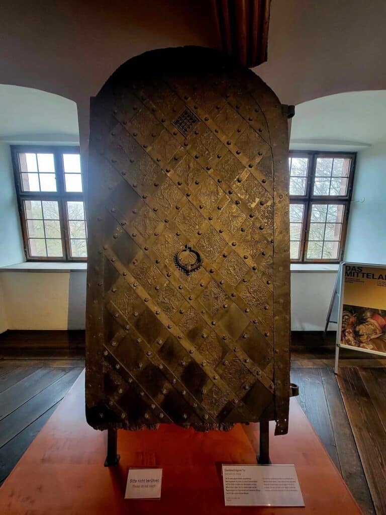 A heavy oak door reinforced with criss cross iron straps, dated to the mid 1600s