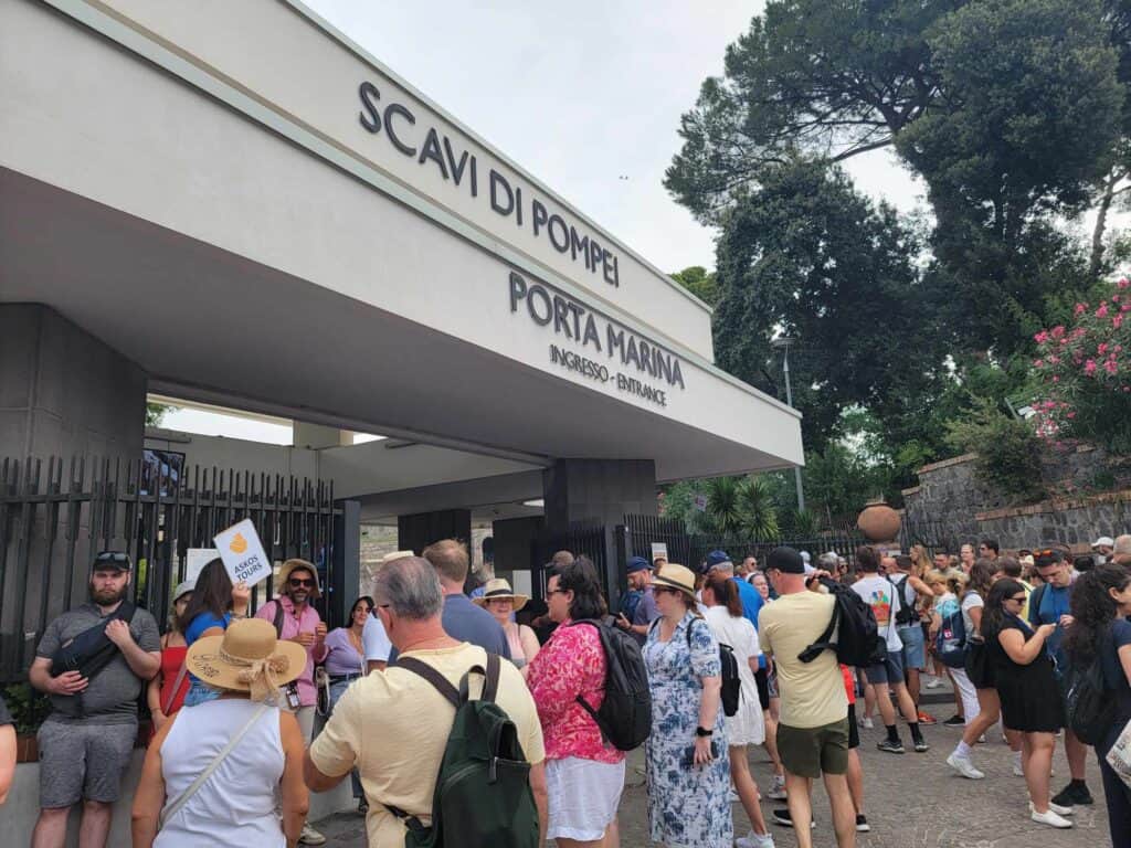 Pompeii vs. Herculaneum: Best Tips & Biggest Differences 27 The entrance gates to Pompeii with a crowd of people waiting to get in