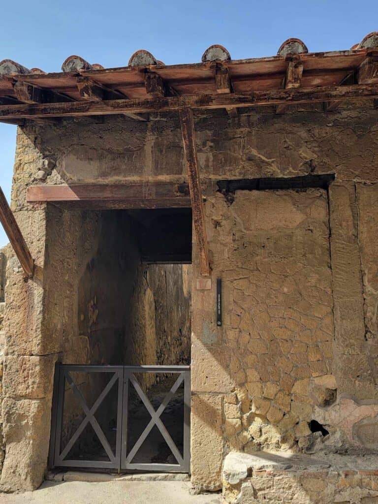 Pompeii vs. Herculaneum: Best Tips & Biggest Differences 18 A stone dwelling with a roof and a tall rectangular door
