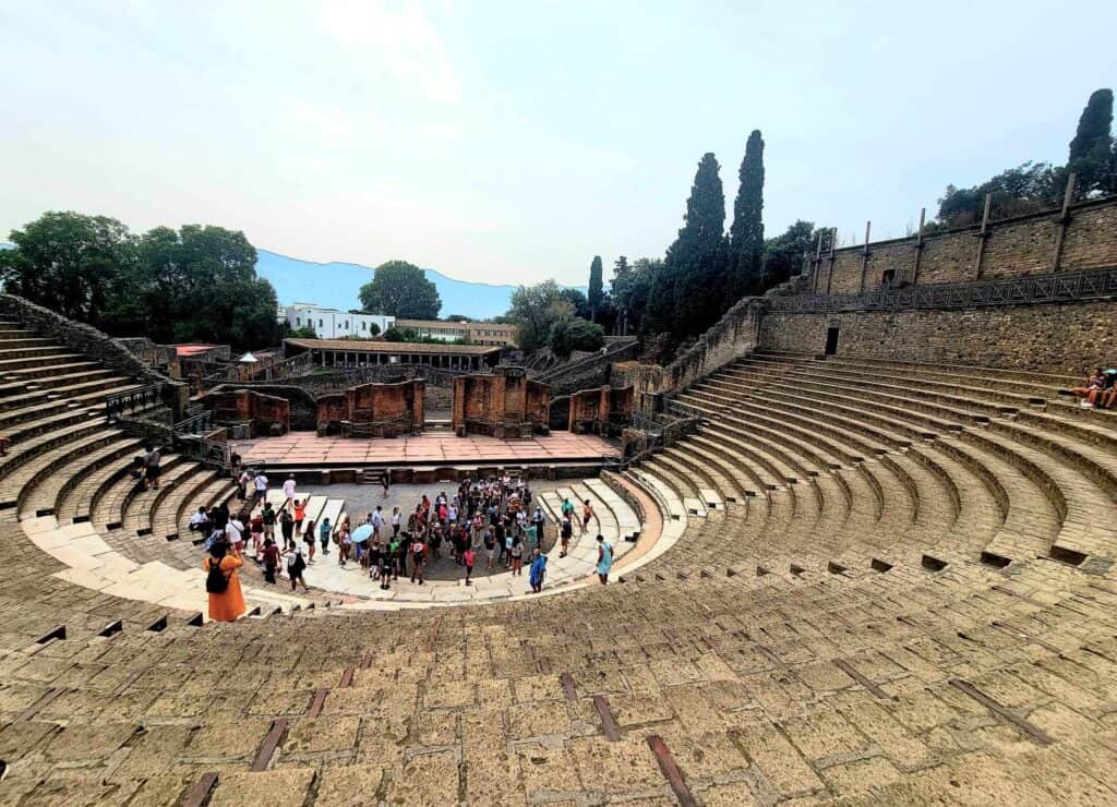 Pompeii vs. Herculaneum: Best Tips & Biggest Differences 2 A group of tourists are on stage in the amphitheater in Pompeii