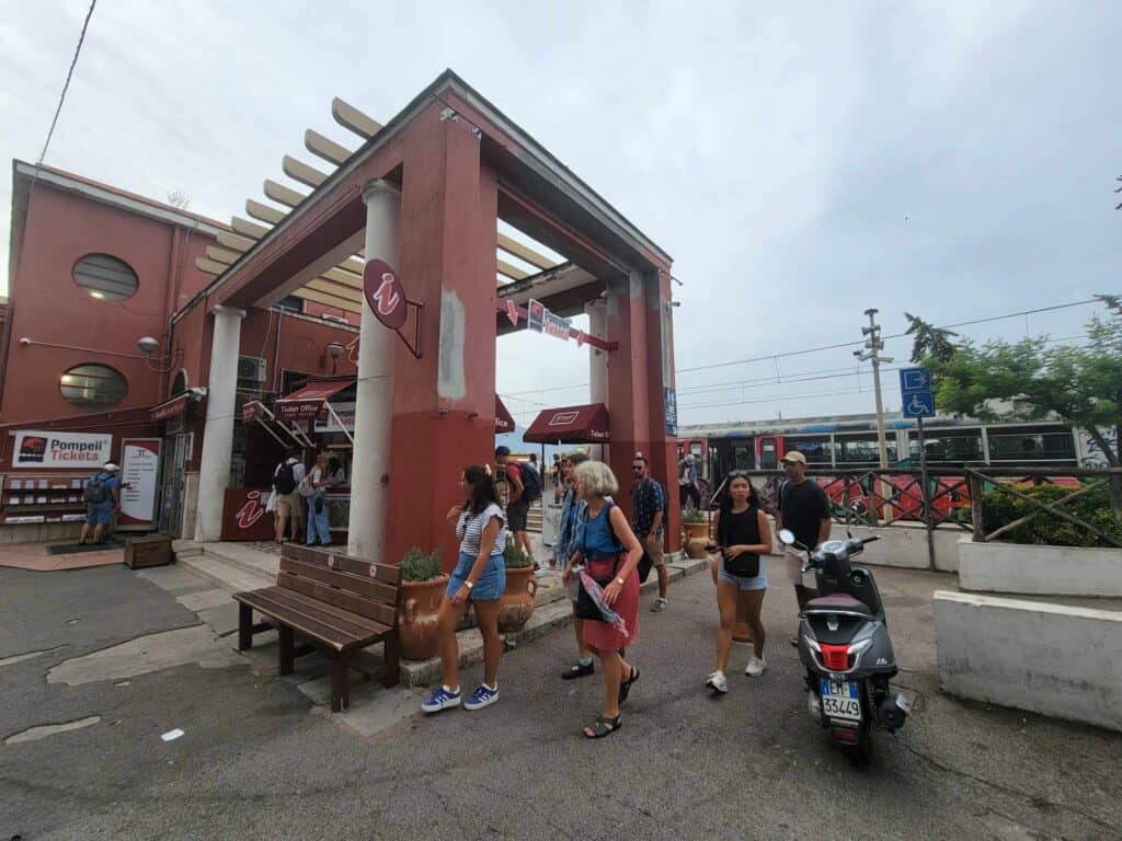 Pompeii vs. Herculaneum: Best Tips & Biggest Differences 8 A bench and a pergola sit near the tourist information center, and a train unloads tourists behind