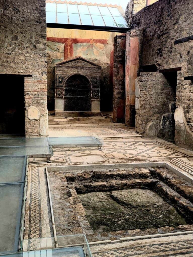 Pompeii vs. Herculaneum: Best Tips & Biggest Differences 3 A beautiful stone interior with mosaic floors and a fountain basin