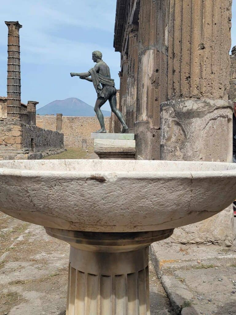 Pompeii vs. Herculaneum: Best Tips & Biggest Differences 17 A large stone basin with a statue of Apollo and stone columns