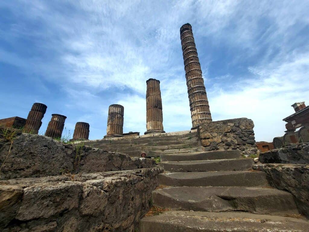 Pompeii vs. Herculaneum: Best Tips & Biggest Differences 16 Worn stone steps leading to the temple of Apollo in Pompeii with a series of broken columns