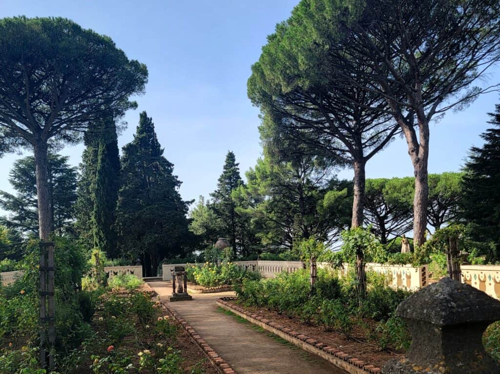 Villa Cimbrone Gardens: The Most Breathtaking View in Italy! 10 The rose garden at Villa Cimbrone Gardens with tall trees, paths lined in stone, rose bushes, and a sundial