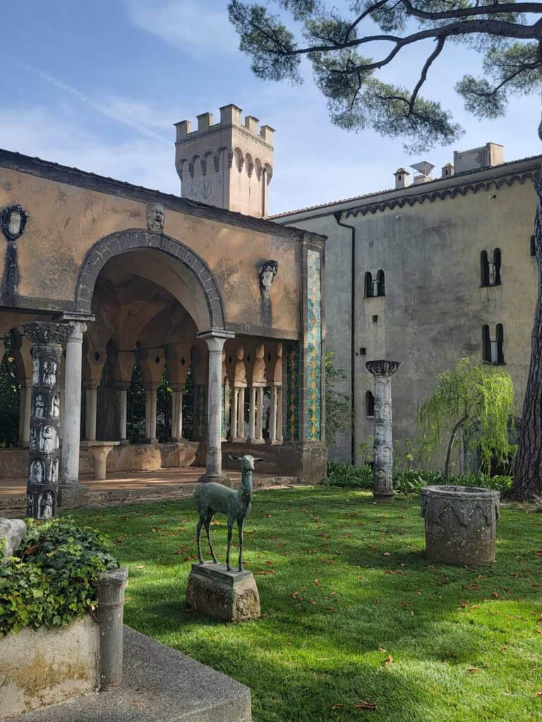 Villa Cimbrone Gardens: The Most Breathtaking View in Italy! 12 Moorish architecture and an outdoor tea room with a sculpture of a deer on the grass and the Villa's tower behind