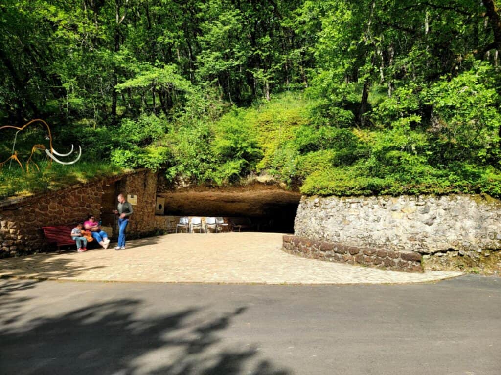 Best 2 Day Dordogne Prehistory Itinerary: What to See & Do 10 A wide but low entrance to the Rouffignac Cave with a bench outside and forest above