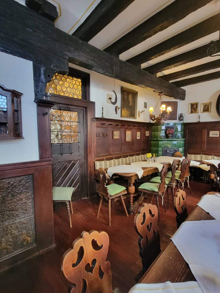 One Day in Bacharach: Best Guide to Germany's Hidden Gem on the Rhine 16 A restaurant interior with carved wooden chairs, leaded windows, timbered ceilings and long wooden tables