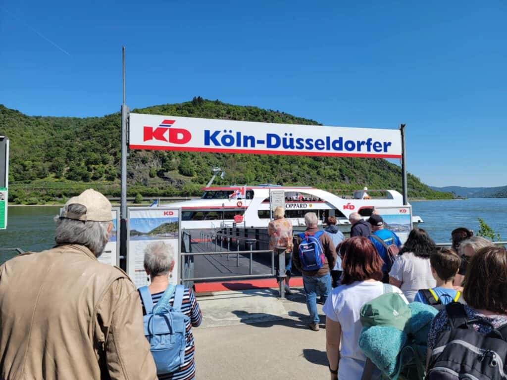 One Day in Bacharach: Best Guide to Germany's Hidden Gem on the Rhine 21 A banner that says Koln-Dusseldorfer with a boat underneath and people waiting to board