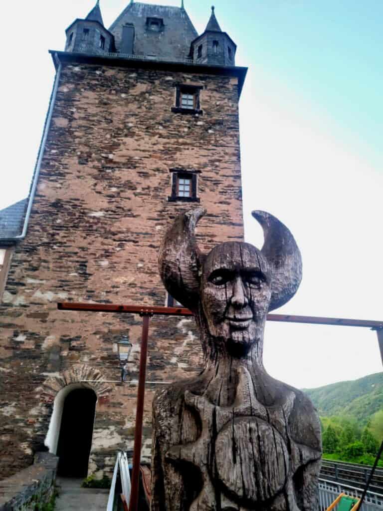 One Day in Bacharach: Best Guide to Germany's Hidden Gem on the Rhine 4 A tall stone square medieval tower with a wooden figure of a woman with large horns and a shield that looks like a sun