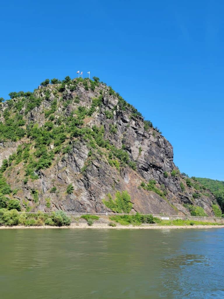 One Day in Bacharach: Best Guide to Germany's Hidden Gem on the Rhine 23 Loreley Rock, a tall geologic formation next to the river with flags and hikers on top