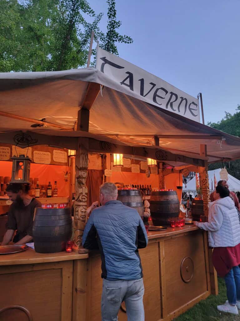 One Day in Bacharach: Best Guide to Germany's Hidden Gem on the Rhine 29 A wooden stall with barrels and a bar, hanging illuminated lanterns and a sign that says TAVERNE