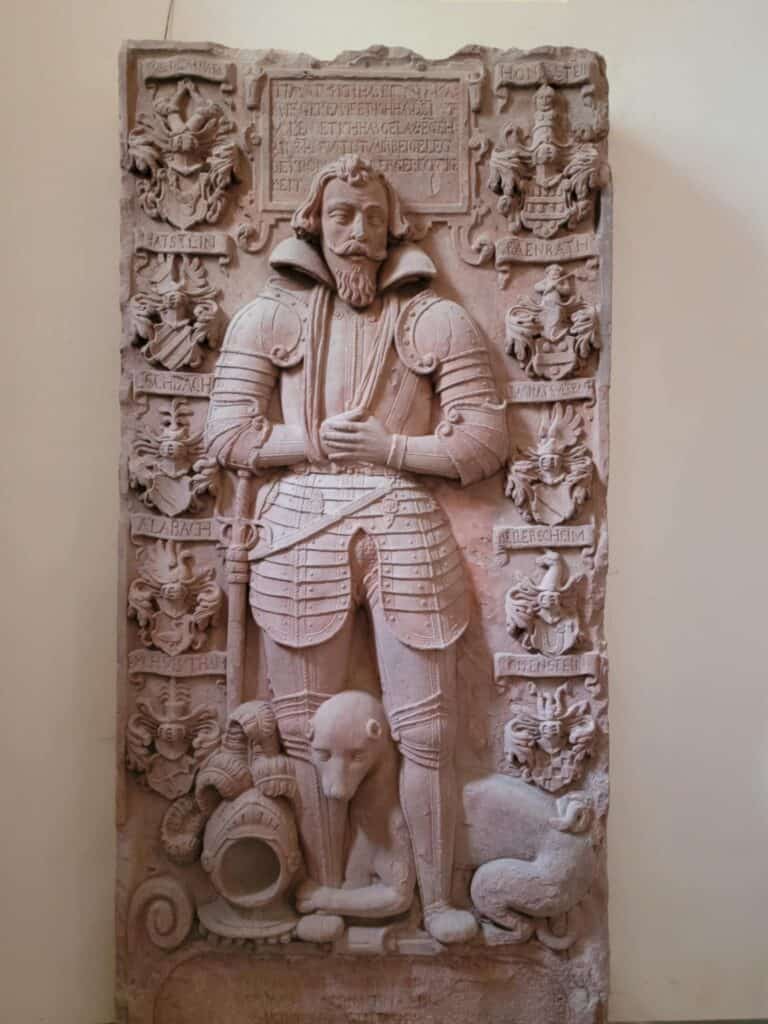 One Day in Bacharach: Best Guide to Germany's Hidden Gem on the Rhine 7 A sandstone tomb cover of a knight in full armor and a dog clutching his ankle