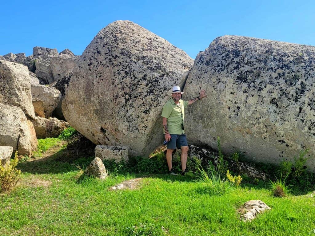 A man stands by massive tumbled columns at Selinunte Archaeological Park in Sicily
