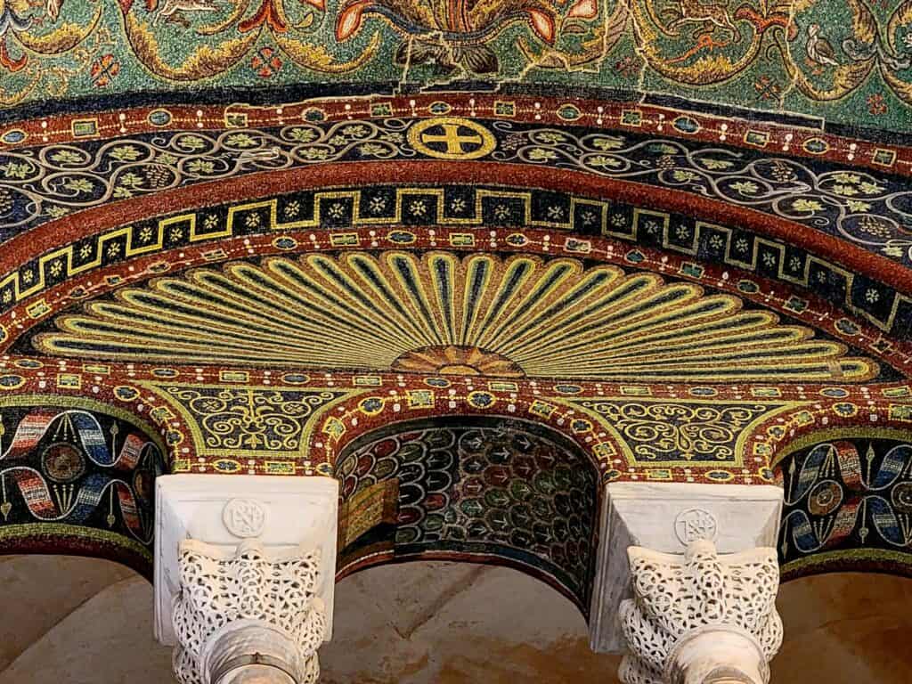 Beautiful columns with elaborate capitals and colorful mosaic ceiling in Ravenna Italy