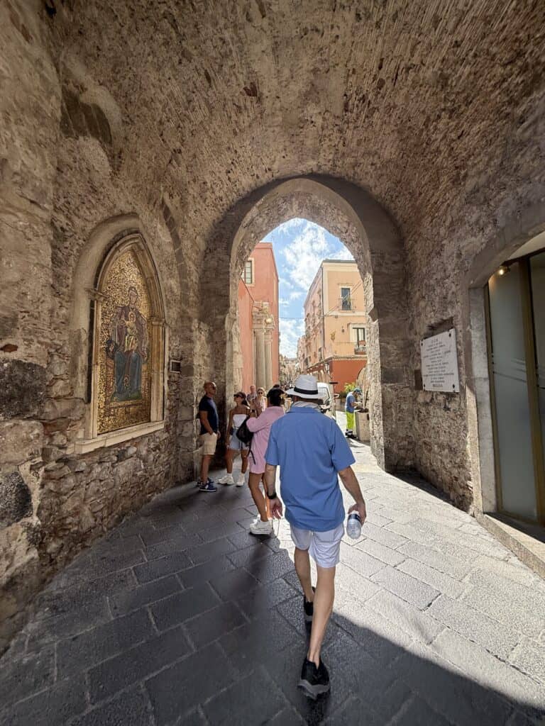 Man walking through a stone passage in Taormina