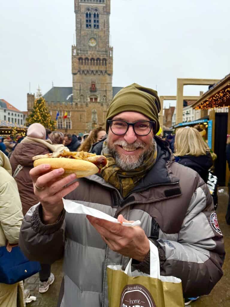 Bruges Christmas Market 2026: Winter Glow, Waffles & an Actual Michelangelo 6 Happy guy with hotdog at the Bruges Christmas market