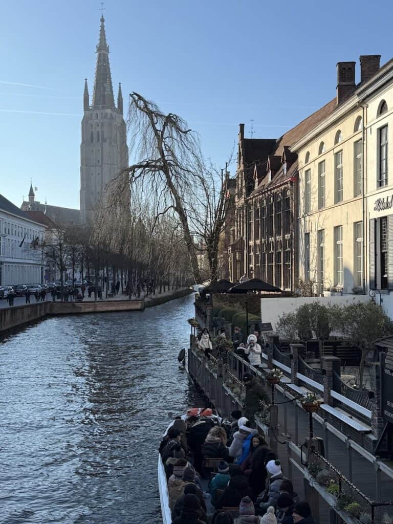 Bruges Christmas Market 2026: Winter Glow, Waffles & an Actual Michelangelo 18 Boat on a canal in Bruges during the Bruges Christmas market