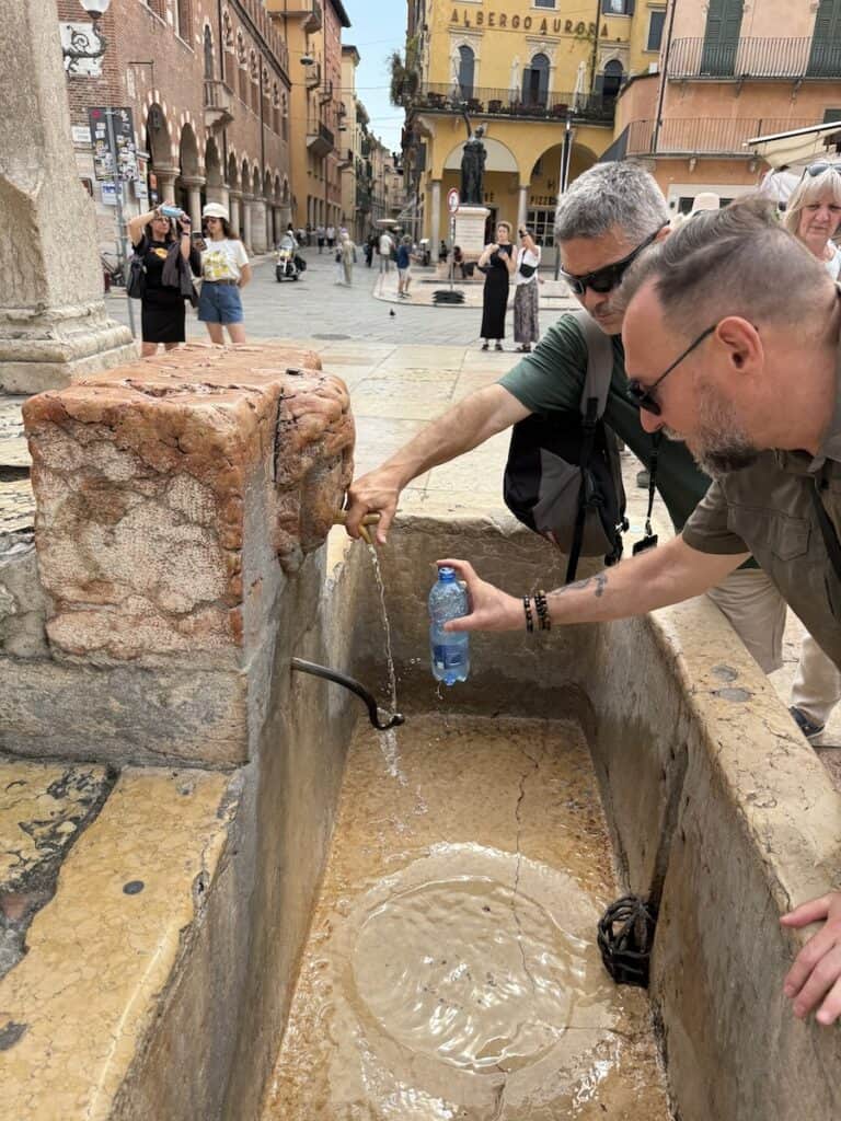 Things to Do in Verona: A 4-Day Guide Beyond Romeo and Juliet 3 Two men filling water bottles at a public fountain in Verona Italy